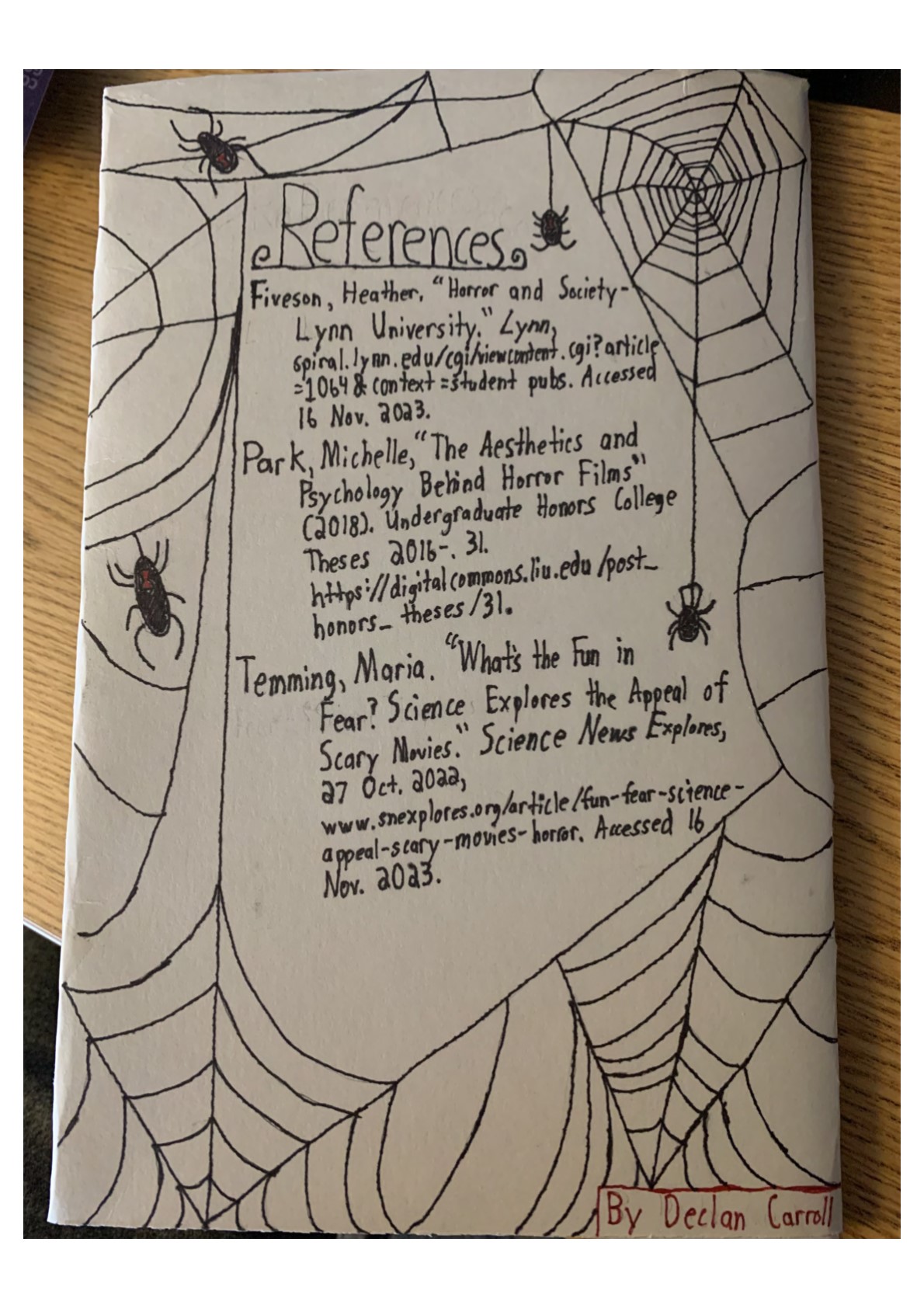 Spiders in spider webs are drawn on the page. 
    “References
    Fiveson, Heather, “Horror and Society – Lynn University.” Lynn, https://spiral.lynn.edu/cgi/viewcontent.cgi?article=1064&context=studentpubs. Accessed 16 Nov. 2023.
    Park, Michelle, “The Aesthetics and Psychology Behind Horror Films” (2018). Undergraduate Honors College Theses 2016-. 31. https://digitalcommons.liu.edu/post_honors_theses/31.
    Temming, Maria. “What’s the Fun in Fear? Science Explores the Appeal of Scary Movies.” Science News Explores, 27 Oct. 2022, https://www.snexplores.org/article/fun-fear-science-appeal-scary-movies-horror. Accessed 16 Nov. 2023.
    By Declan Carroll”